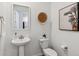 Modern powder room with a pedestal sink, decorative mirror, and stylish wall art, offering a chic touch at 2036 S Vance Way, Lakewood, CO 80227