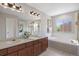 Bathroom with double sink vanity, soaking tub, glass-enclosed shower, and a window for natural light at 9810 Townsville Cir, Highlands Ranch, CO 80130
