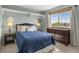 Comfortable bedroom with a queen bed, modern dark wood dresser and views of the outdoors at 9810 Townsville Cir, Highlands Ranch, CO 80130