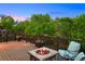 Deck with a fire pit, seating, and scenic views of the backyard and lush trees at 9810 Townsville Cir, Highlands Ranch, CO 80130