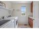 Functional laundry room includes a washer, dryer, storage cabinets, and a window for natural light at 9810 Townsville Cir, Highlands Ranch, CO 80130