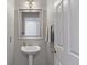 A pristine powder room features a pedestal sink, decorative mirror, and updated lighting at 9810 Townsville Cir, Highlands Ranch, CO 80130