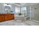 Bright bathroom featuring double vanity, soaking tub and glass enclosed shower stall with tile surround at 10824 Quail Ridge Dr, Parker, CO 80138
