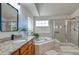 Bright bathroom featuring double vanity, soaking tub and glass enclosed shower stall with tile surround at 10824 Quail Ridge Dr, Parker, CO 80138