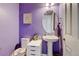 Stylish powder room features a pedestal sink, oval mirror, and a fresh purple paint color at 282 Vialpando St, Brighton, CO 80601