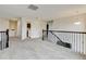 Carpeted upstairs landing with dark banister leads to hallway and laundry room at 282 Vialpando St, Brighton, CO 80601