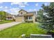 Inviting two-story home with lush green lawn, mature tree, bench, and well-manicured landscaping at 10530 Mount Columbia Pl, Parker, CO 80138
