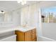 Well-lit bathroom featuring a vanity with wooden cabinets, a shower with curtains, and a window at 1960 Hudson St, Denver, CO 80220