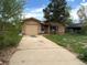 A single-story home with a brick exterior, attached garage, and a concrete driveway at 1890 Eaton St, Lakewood, CO 80214