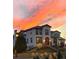 Elegant two-story home featuring a tile roof and decorative holiday lights beneath a vibrant sunset sky at 27061 E Long Cir, Aurora, CO 80016