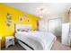 Bright bedroom with a white bed, yellow accent wall, and modern lighting fixture at 14595 Robins Dr, Denver, CO 80239