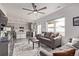 Open-concept living room with gray sofa, modern ceiling fan and view into the kitchen at 515 Bridger Ave, Fort Lupton, CO 80621