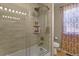 Tiled bathroom features a glass shower with shampoo niche and unique shower curtain at 17332 E Lake Ln, Aurora, CO 80016
