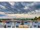 Aerial view showcases a neighborhood featuring modern, multi-story homes under a dramatic cloudy sky, set against distant mountain views at 2473 S Cherokee St, Denver, CO 80223