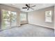 A minimalist bedroom with plush carpet, a ceiling fan, and sliding doors to a balcony at 2473 S Cherokee St, Denver, CO 80223
