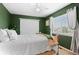 Cozy bedroom showcasing a large window with blinds, green walls, and a comfortable bed at 10197 Quintero St, Commerce City, CO 80022