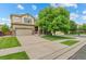 Lovely two-story home with manicured lawn, mature tree, and convenient two-car garage under a bright blue sky at 10197 Quintero St, Commerce City, CO 80022