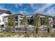 Contemporary home with a gray fence and carefully manicured landscaping, set against a partly cloudy sky at 7125 Skygazer St, Castle Pines, CO 80108