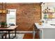 Charming dining room features a brick wall, wood table, and open view to a modern kitchen at 1452 S Logan St, Denver, CO 80210