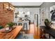 Hardwood floors in an open dining area featuring an exposed brick wall, white kitchen and modern lighting fixtures at 1452 S Logan St, Denver, CO 80210