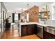 Open-concept living room featuring hardwood floors, exposed brick wall, modern lighting, and updated kitchen with stainless appliances at 1452 S Logan St, Denver, CO 80210