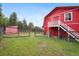 Exterior view of a charming red barn featuring fencing and a grassy yard at 31551 Black Widow Dr, Conifer, CO 80433