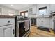 Modern kitchen with stainless steel range, white cabinets, granite countertops, and hardwood flooring at 31551 Black Widow Dr, Conifer, CO 80433