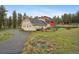 Home and outbuildings on a large treed lot showing expansive green lawn and gravel driveway at 31551 Black Widow Dr, Conifer, CO 80433