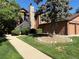 Charming townhouse shows a stone chimney, a wooden staircase and grassy lawn and pathway leading to the building at 9483 W 89Th Cir, Broomfield, CO 80021