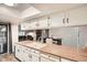 Bright kitchen with wood counters, white cabinets, and stainless steel appliances and views into dining and living area at 9483 W 89Th Cir, Broomfield, CO 80021