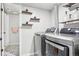 Well-organized laundry room with modern washer/dryer, floating shelves, and adjacent bathroom area at 19003 E Oxford Dr, Aurora, CO 80013