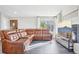 Cozy living room featuring a large brown leather sofa, a large window, and luxury vinyl flooring at 19003 E Oxford Dr, Aurora, CO 80013