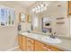 A full bathroom with a large mirror reflecting double sinks with wood cabinets and ample lighting at 19463 E Hollow Creek Dr, Parker, CO 80134