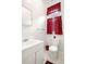 Neat white-tiled bathroom with a modern sink, toilet, and bright red accents at 2146 Federal Blvd, Denver, CO 80211