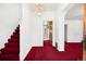 Bright hallway featuring staircase, chandelier, fresh white walls, and bright red carpeting at 2146 Federal Blvd, Denver, CO 80211