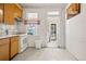 This kitchen features wood cabinets, white appliances, and a window with decorative curtains at 2146 Federal Blvd, Denver, CO 80211