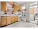 A quaint kitchen is shown, featuring wood cabinets, white appliances and a patterned curtain at 2146 Federal Blvd, Denver, CO 80211