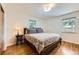 Cozy bedroom features a queen-sized bed, wood floors, two windows, and a side table with lamp at 1600 Olive St, Denver, CO 80220