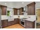 A modern kitchen with brown cabinets, stainless steel appliances, and a farmhouse sink under a bright window at 1600 Olive St, Denver, CO 80220