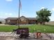Charming brick home featuring a well-maintained lawn, mature tree, and unique mining cart decor at 16535 W 79Th Dr, Arvada, CO 80007