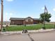 Charming brick home featuring a well-maintained lawn, mature tree, and unique mining cart decor at 16535 W 79Th Dr, Arvada, CO 80007