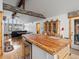 A kitchen island with seating and wood countertops in an open concept home with vaulted ceilings and rustic wood beams at 16535 W 79Th Dr, Arvada, CO 80007