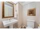 Powder room featuring a pedestal sink, toilet, ornate mirror, and decorative wallpaper at 1900 E Girard Pl # 908, Englewood, CO 80113