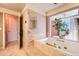 Relaxing bathtub with jets surrounded by tile and large window view to outside at 1900 E Girard Pl # 908, Englewood, CO 80113