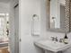Clean white bathroom with a pedestal sink, decorative mirror, and a neutral color scheme at 3476 Beeler Ct, Denver, CO 80238