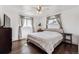 Primary bedroom featuring a ceiling fan, hardwood floors, and two large windows with decorative curtains at 8641 Lowell Blvd, Westminster, CO 80031