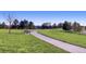 Scenic park featuring a paved walking path, lush green grass, mature trees, and a bench at 23580 E Portland Way, Aurora, CO 80016