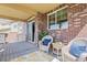 Covered patio with brick accents, wicker seating and a view of the home's exterior at 23580 E Portland Way, Aurora, CO 80016