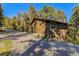 Charming home featuring wood siding, gravel driveway, and nestled amid towering trees in the countryside at 31084 Kings Valley Dr, Conifer, CO 80433