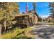 Charming home featuring a front porch, wood siding, and a gravel driveway surrounded by lush trees at 31084 Kings Valley Dr, Conifer, CO 80433